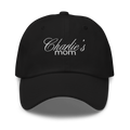 Black baseball cap featuring white embroidered text Charlie's mom in a decorative script font above a simpler sans-serif font highlighting the fabric texture and stitching details