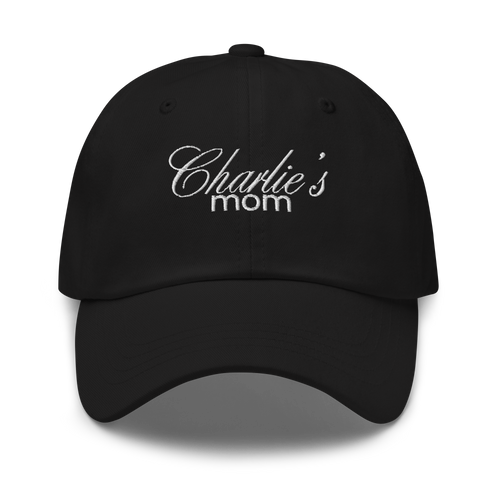 Black baseball cap featuring white embroidered text Charlie's mom in a decorative script font above a simpler sans-serif font highlighting the fabric texture and stitching details