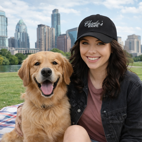 Woman with a black cap and a golden dog sitting on a blanket in a park with city Austin TX skyline in the background